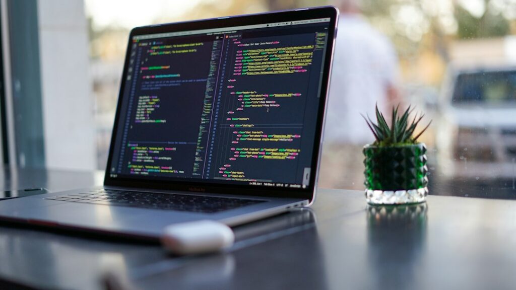 Laptop showing code on a desk next to a plant, used to compare Wayback Machine downloader alternatives